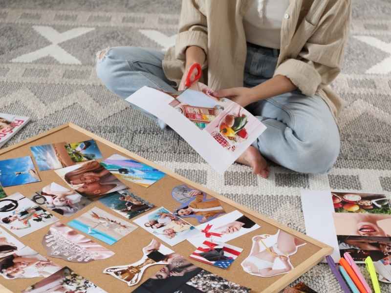 mujer sentada en el piso recortando imágenes para su vision board