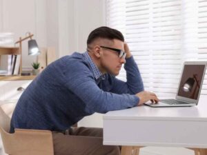 hombre trabajando sentado con una mala postura frente a la laptop