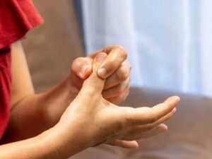 mujer masajeándose las manos que parecen estar inflamadas por retención de líquidos