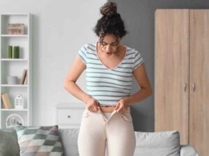 mujer intentando entrar en unos jeans que parecen ya no cerrar